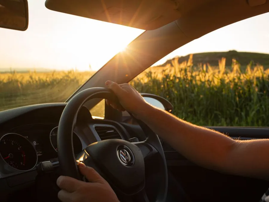 Vue du conducteur sur une route de campagne au volant, mains sur le volant.